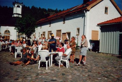 En grupp människor samlade runt trädgårdsmöbler på en innergård
Nyckelord: Café Servering