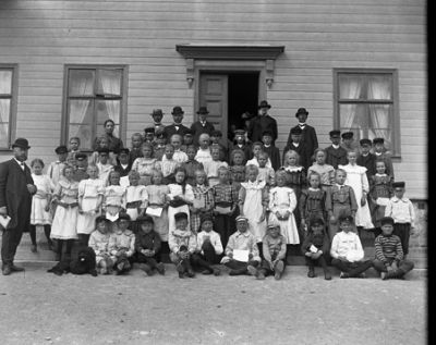 Skolklass med lärare framför skola
Nyckelord: Skolfotografi