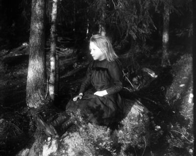 Flicka sittande på sten
