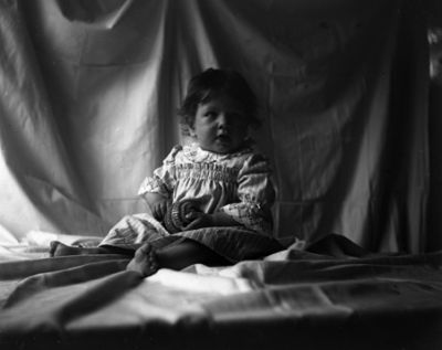 Liten flicka sittande bland skynken
Nyckelord: Barnfoto