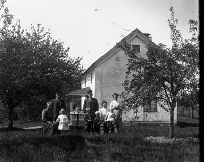 En grupp människor samlade i trädgård
Nyckelord: Familj vid hus