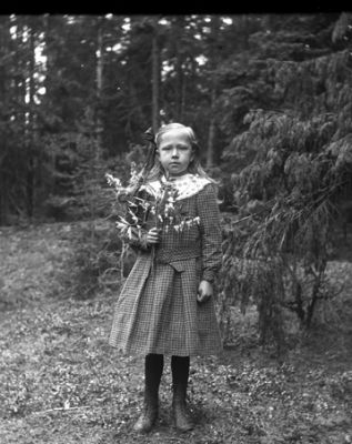 Flicka stående i skogen med blomma i handen
Nyckelord: Klänning