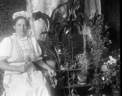 Kvinna sittande bland krukväxter
Nyckelord: Arbetsklädsel Blommor Krukväxter