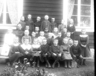 Skolklass med lärarinna framför byggnad
Nyckelord: Klassfoto Skolfoto Klänning Kostym Spetskrage