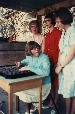 3 kvinnor stående bakom kvinna med instrument
Nyckelord: Sittra 