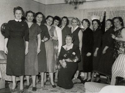 11 stående kvinnor och kvinna sittande med blommor i famnen
Nyckelord: Uppvaktning