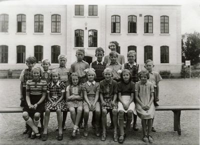 Kvinna och barn sittande och stående på skolgård
Nyckelord: Elever, Skolbyggnad, Skolklass, Skolfotografi, Klassfotografi