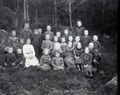 Kvinna med en grupp barn i skogsbacke
Nyckelord: Skola