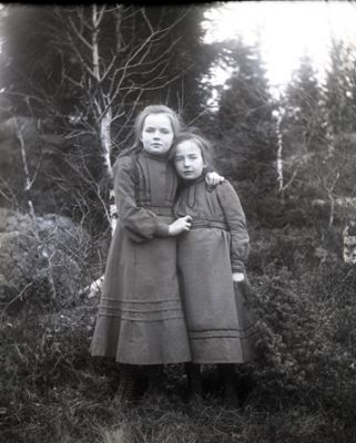 2 flickor stående i skogsbryn
Nyckelord: Dräkt