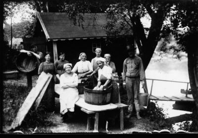 5 kvinnor och två män tvättar kläder.
Nyckelord: Bykkar