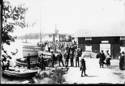 Ett antal personer på båt och brygga.
Nyckelord: Folksamling