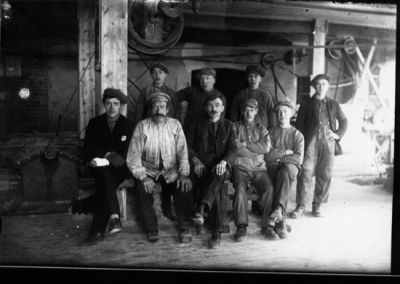 5 sittande män och 4 stående i industrilokal.
Nyckelord: Skeppsdockan