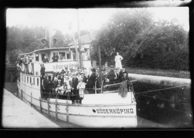 Ett antal personer stående på kanalbåt i slussen.
Nyckelord: Kanalbåt Folksamling