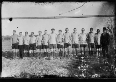 15 stående fotbollsspelare framför fotbollsmål.
Nyckelord: Fotbollslag