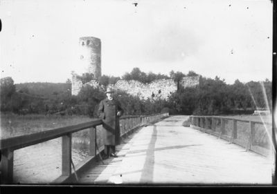 Man stående på bro framför fornminne.
Nyckelord: Vatten