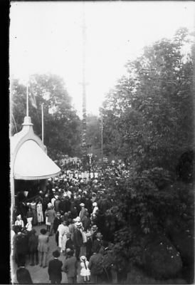 Ett antal personer vid musikpaviljong.
Nyckelord: Folksamling Festlighet Majstång