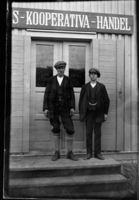 2 ungdomar stående framför affärsdörr.
