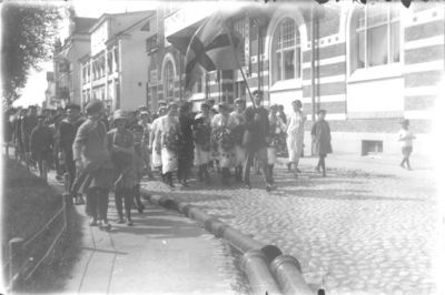 Ett antal gående personer.
Nyckelord: Kortege Flagga