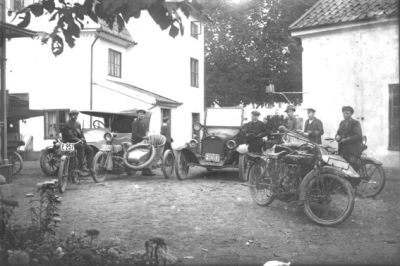7 män bland bilar och motorcyklar.
Nyckelord: Bil Motorcykel