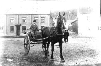 Man i hästekipage på torg.
Nyckelord: Häst Vagn