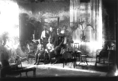 Familj sittande i finrum.
Nyckelord: Möbler