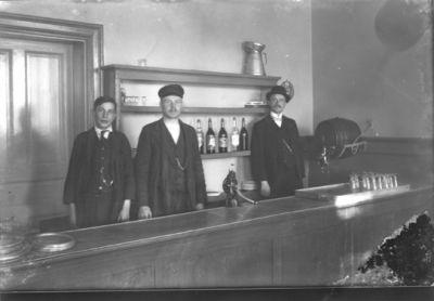 3 män stående bakom bardisk.
Nyckelord: Bar