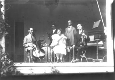 4 män och en kvinna sittande på estrad.
Nyckelord: Musikkapell Instrument