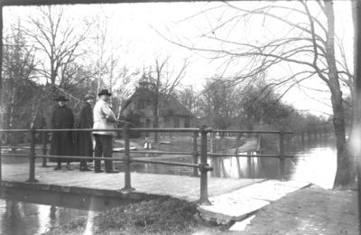 Man och 2 kvinnor stående på bro över ån.
