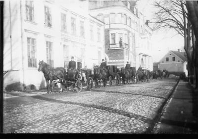 Begravningståg på gata.
Nyckelord: Häst Hotell
