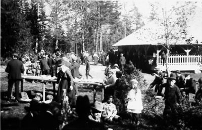 Ett antal personer vid festligheter.
Nyckelord: Långbord