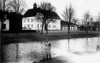 Flicka stående vid vattendrag framför byggnad.
Nyckelord: Vattendrag