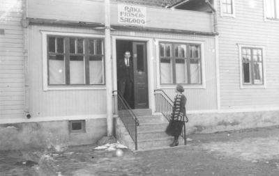 Man och kvinna stående på trappa till frisersalong.
Nyckelord: Trappa