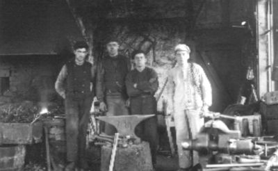4 män stående i smedja.
