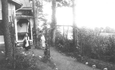 2 kvinnor stående framför byggnad.
Nyckelord: Trädgård Trappa Veranda