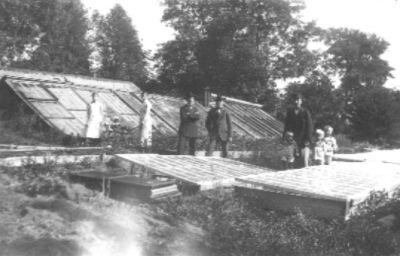 3 män och 3 barn stående bland drivbänkar.
Nyckelord: Drivbänk Växthus