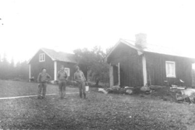 3 män stående framför Byggnad.
Nyckelord: Landsbygd
