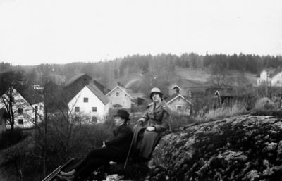 Man och kvinna sittande på berg framför byggnader.
