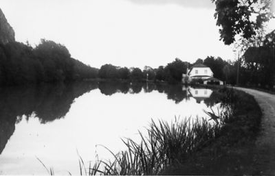 Byggnader bakom vattendrag.
