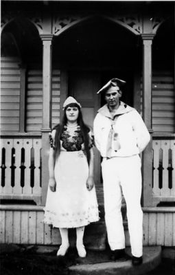 Man och kvinna stående framför byggnad.
Nyckelord: Dräkt