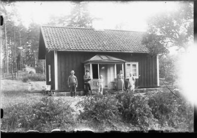 5 personer stående framför byggnad.

