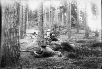 Ett antal män liggande med gevär.
Nyckelord: Gevär Skog