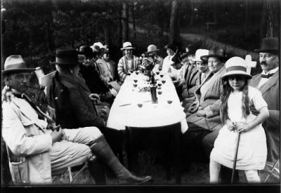 Ett antal personer sittande runt kaffebord.
Nyckelord: Trädgård Kaffebord Dräkt