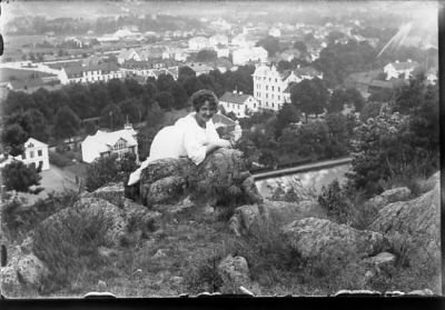 Kvinna sittande på berg med bebyggelse i bakgrunden.
Nyckelord: Utsikt