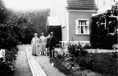 Man och 2 kvinnor stående framför byggnad.
Nyckelord: Hund Trädgård