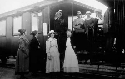 8 kvinnor stående vid och på järnvägsvagn.
