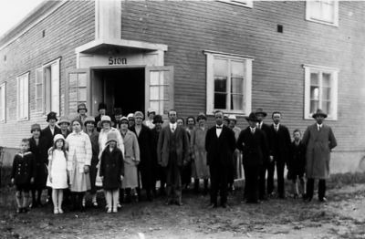 Församling stående framför sin lokal.
