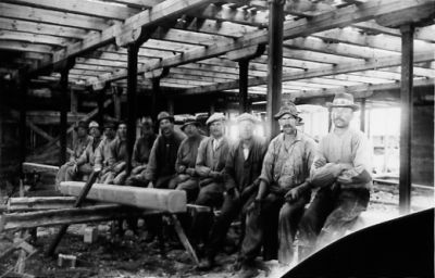 11 män sittande på sågbänk.
Nyckelord: Sågarbete