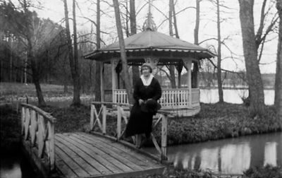 Kvinna sittande på räcke vid vatten.
