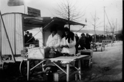 Man och kvinna stående bakom torgstånd.
Nyckelord: Vagn