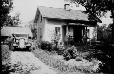 Man och 2 barn stående vid bil bredvid byggnad.
Nyckelord: Bil